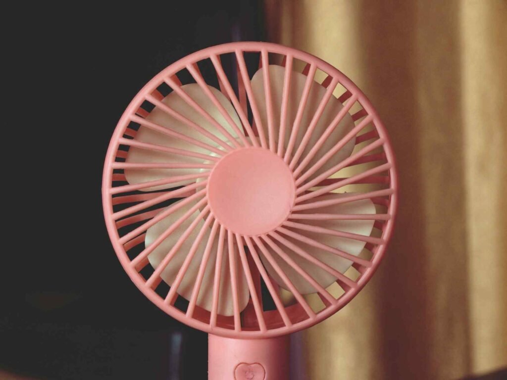 A pink fan standing on top of a table.