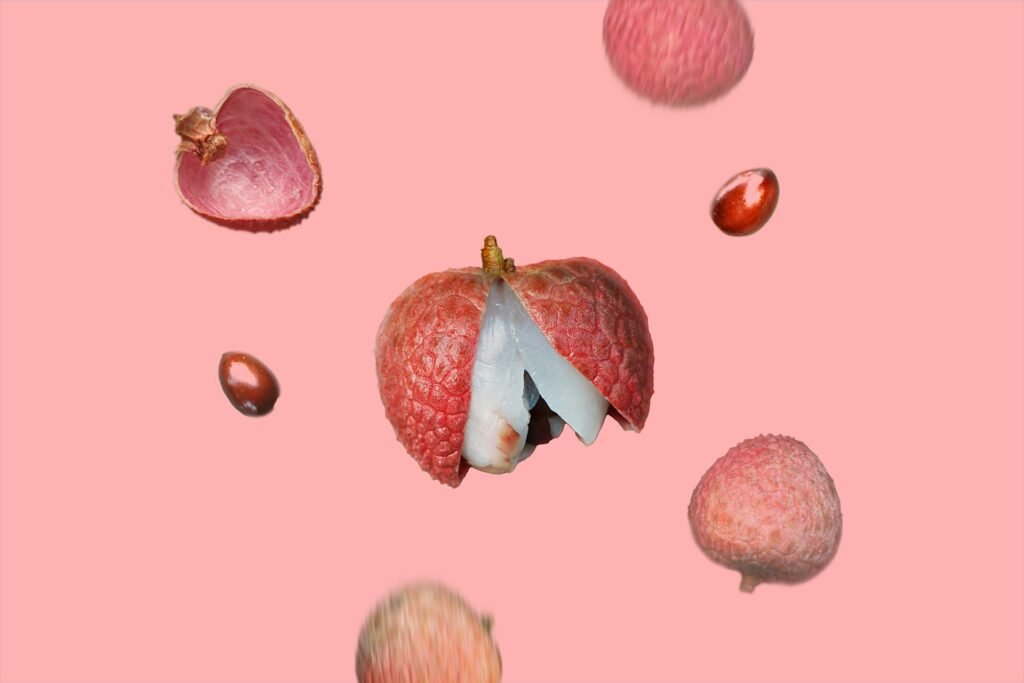 Lychee fruits in the air on a pink background.