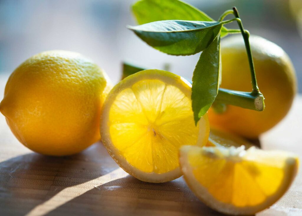 Whole and cut lemons on a wooden table.
