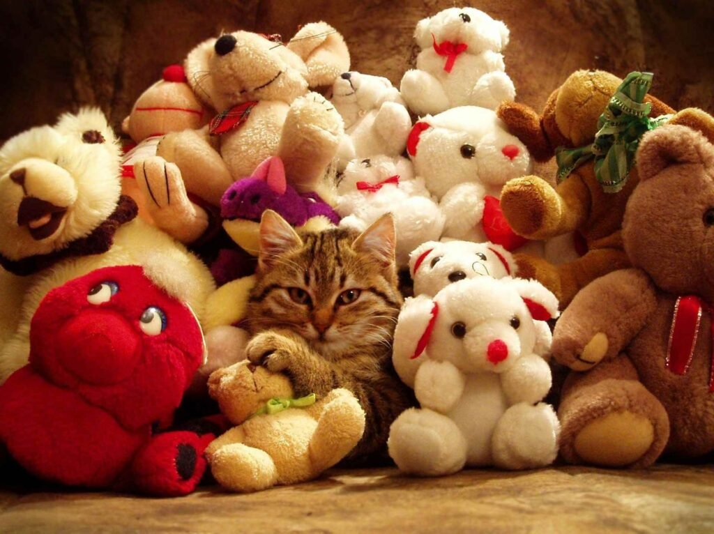 A brown tabby cat under a pile of plush toys and characters.