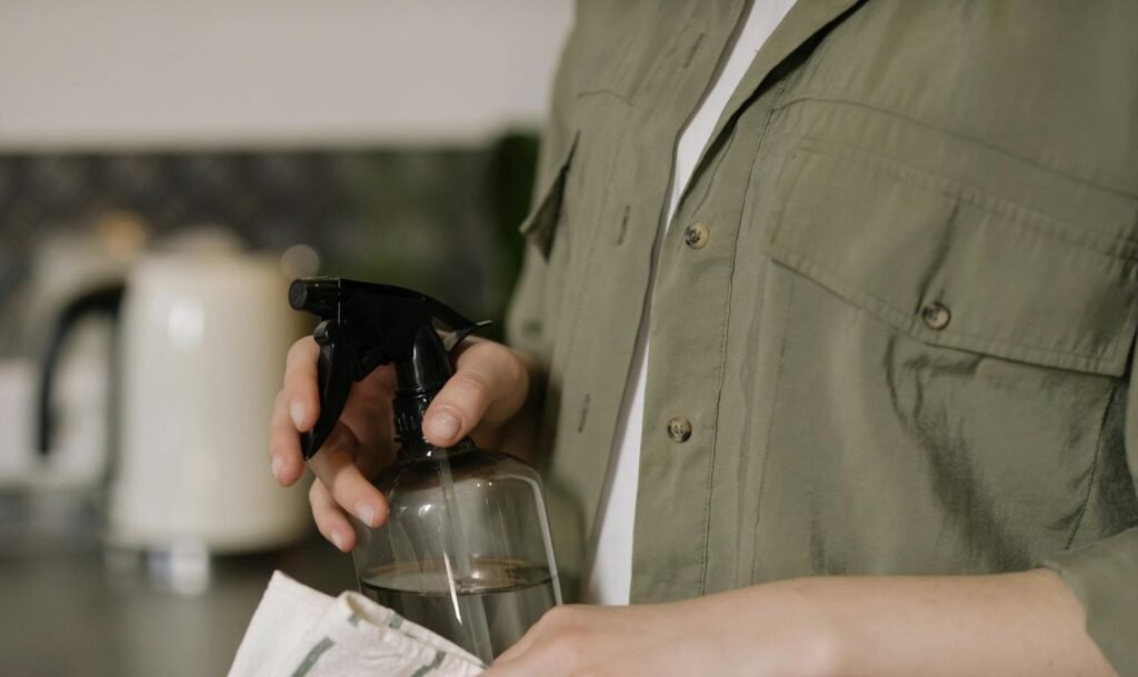 A person aiming a water spray bottle at the kitchen counter.