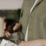 A person aiming a water spray bottle at the kitchen counter.