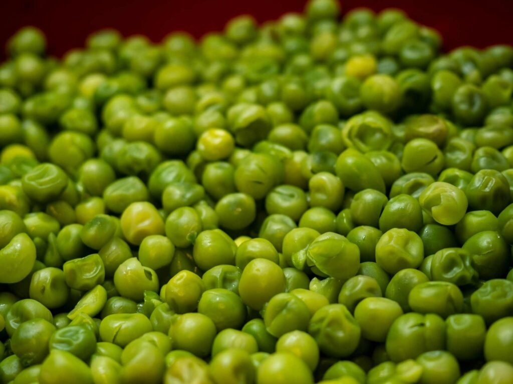 A red container filled with green peas.